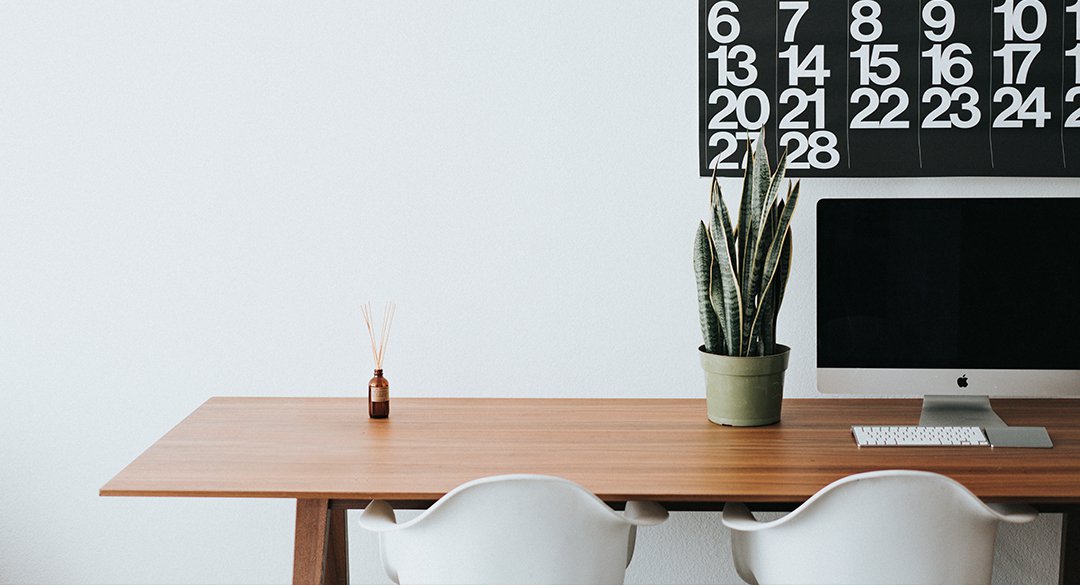 Desk with white chairs, plant, and computer monitor