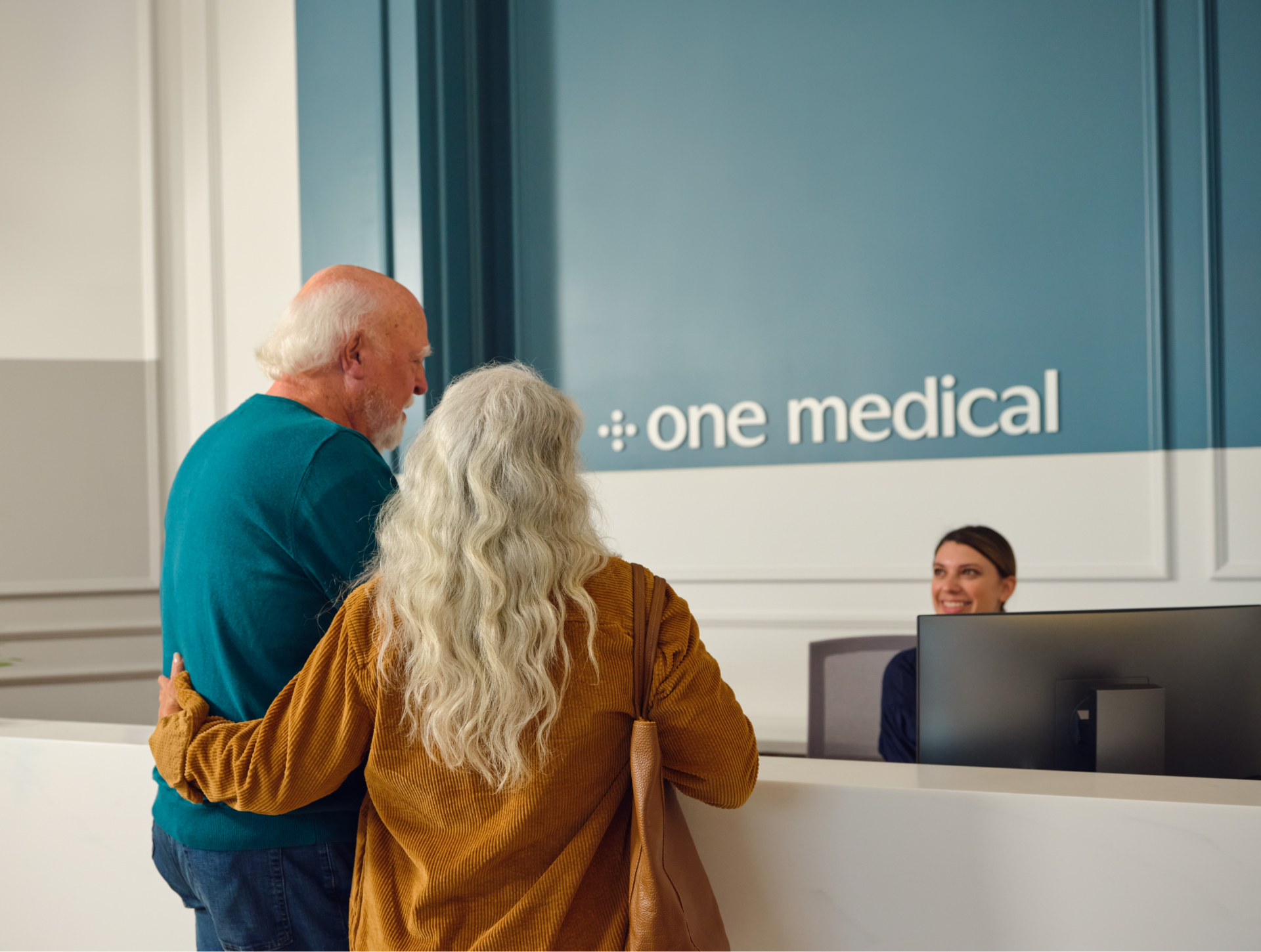 male female couple standing at one medical front desk.png