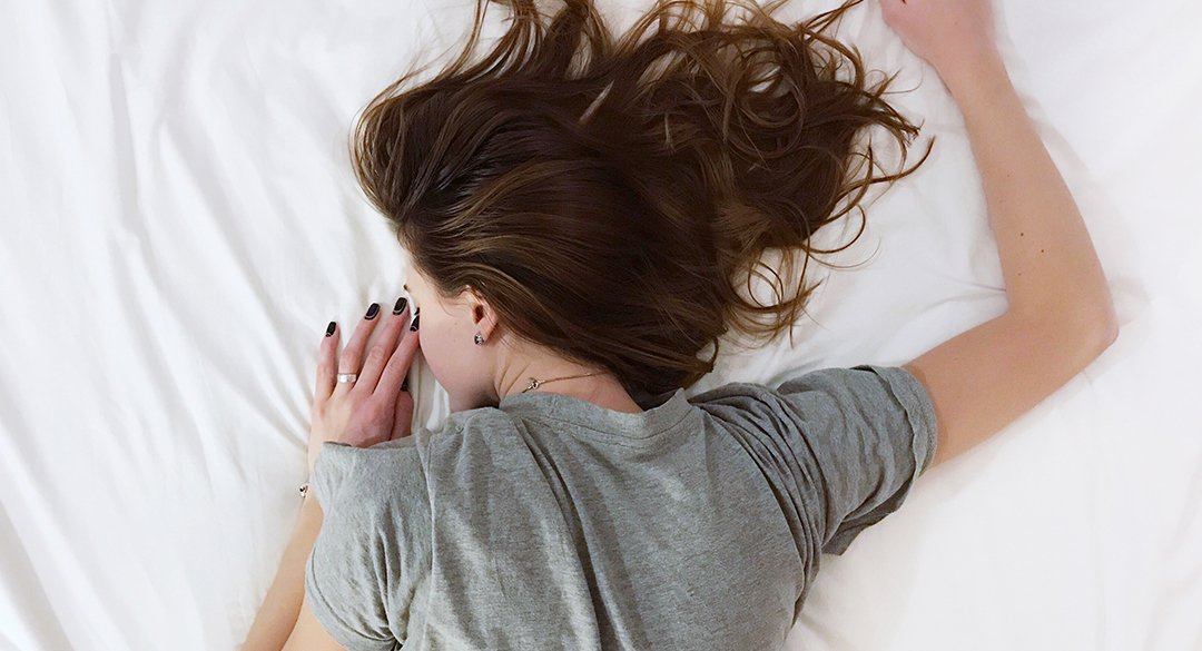 Woman sleeping on a bed with white sheets