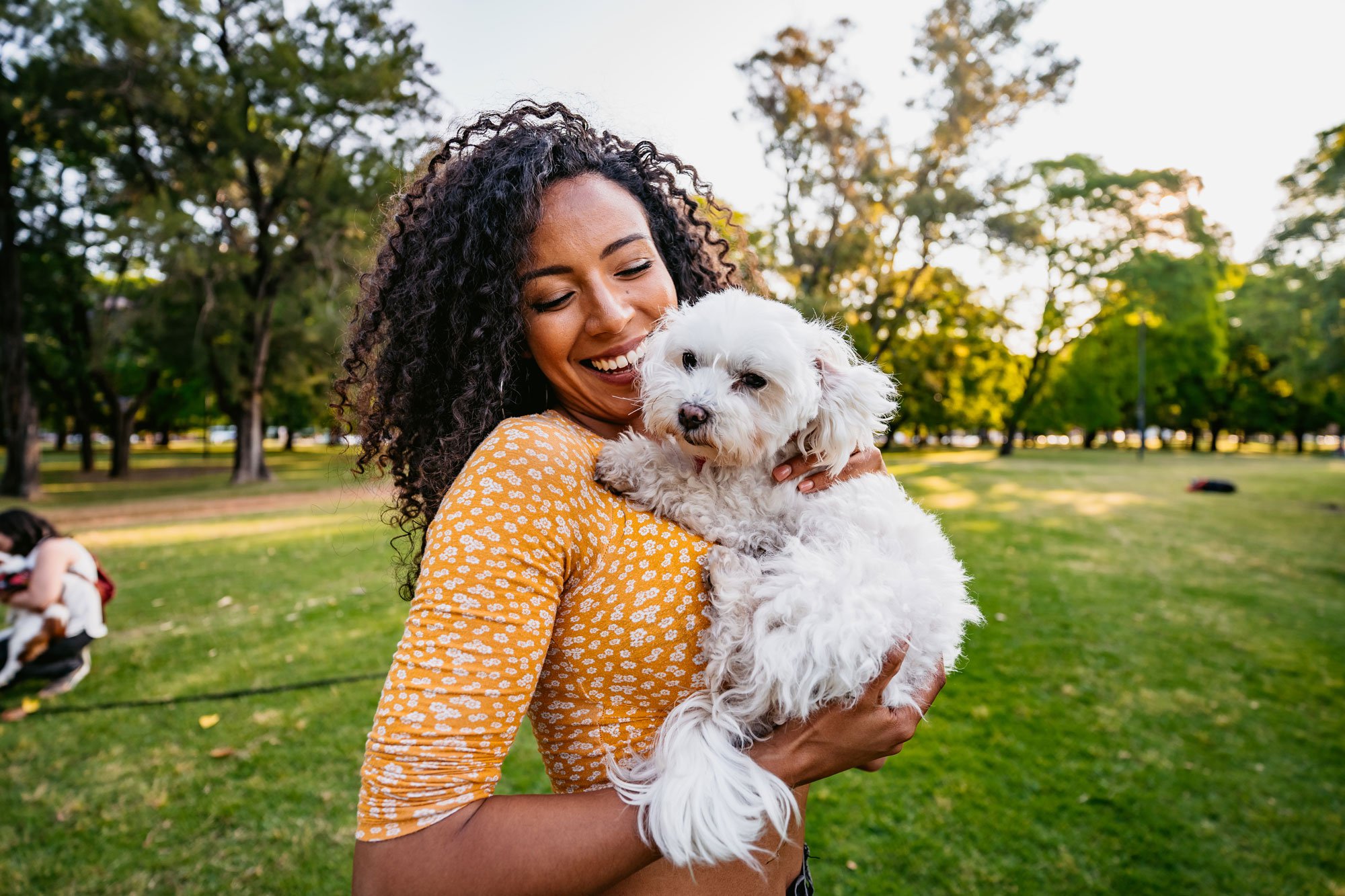 Woman outside holding small white dog