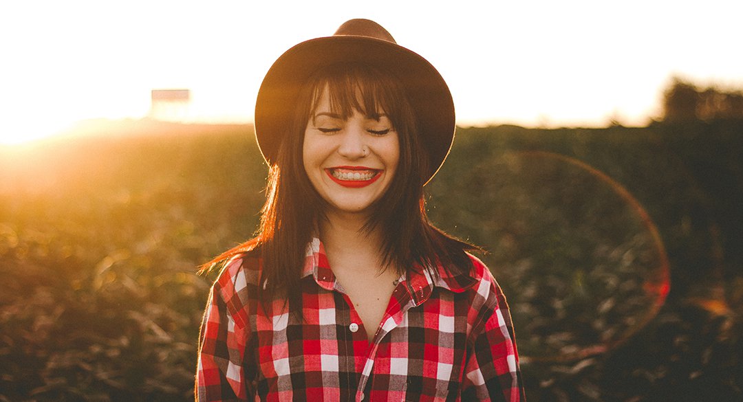 Woman wearing hate and smiling in the sunset