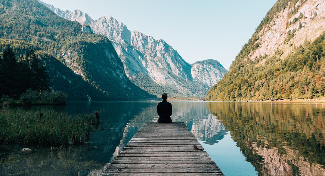 Person sitting on dock on lake