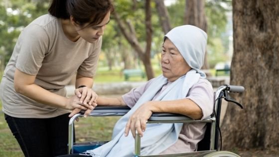 A despondent senior woman sits in a wheelchair with a young woman holding her hand-10.jpeg
