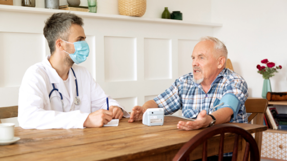 A doctor wearing a mask talks with a senior man in his home while taking his blood pressure-15.png
