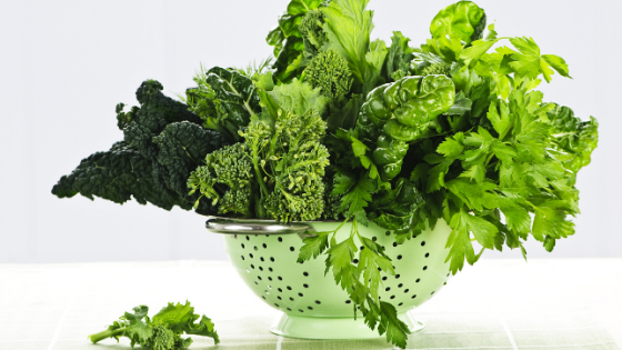 A mint green colander overflows with leafy greens-2.png