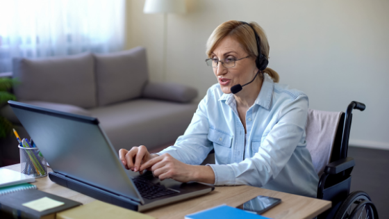 A paraplegic senior woman wears a headset as she answers calls on the computer -3.png