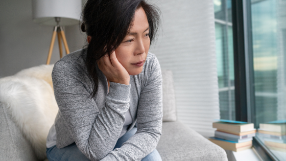 A sad looking Asian senior woman sits up on her couch-2.png
