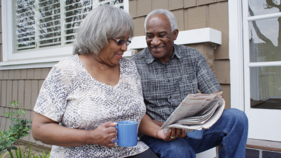 A senior couple sits outside drinking coffee and reading the paper-3.png