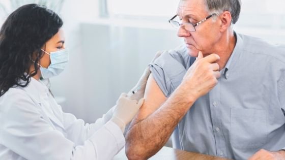 A senior man can be seen getting his yearly flu shot at his doctor's office-2.jpeg