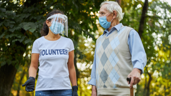 A senior man volunteers outdoors with a volunteer group while wearing a mask-9.png