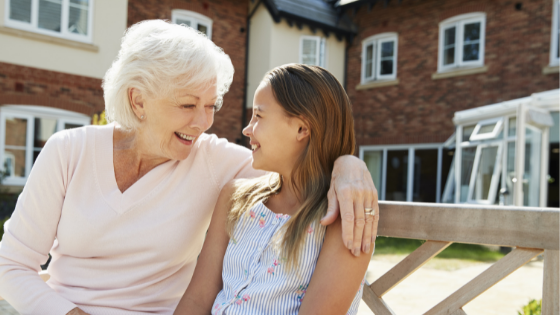 A senior woman and her granddaughter sit on a bench talking-4.png