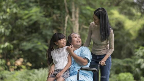 A senior woman in a wheelchair lets her granddaughter sit in her lap while talking to her daughter-3.png