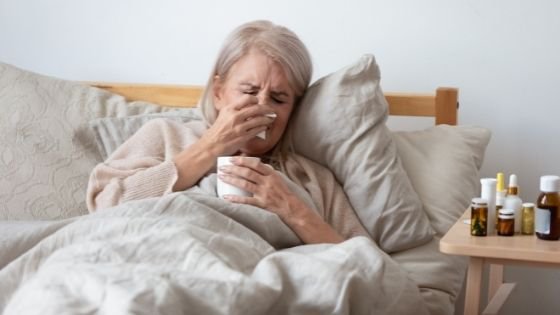 A senior woman is seen sick in bed surrounded by medications-5.jpeg
