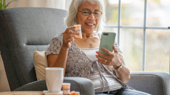 A senior woman shows her prescription bottle to her doctor on a telehealth visit using her smartphone-7.png