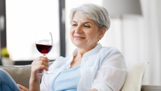 A senior woman sits on the couch holding a glass of red wine-6.png