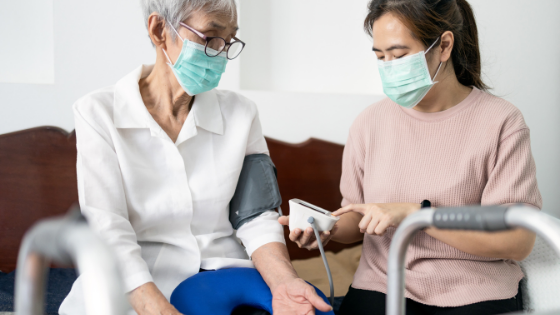 A woman wearing a mask checks a senior woman's blood pressure-1.png