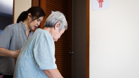 A young caregiver is seen helping a senior woman into a bathoom-5.png