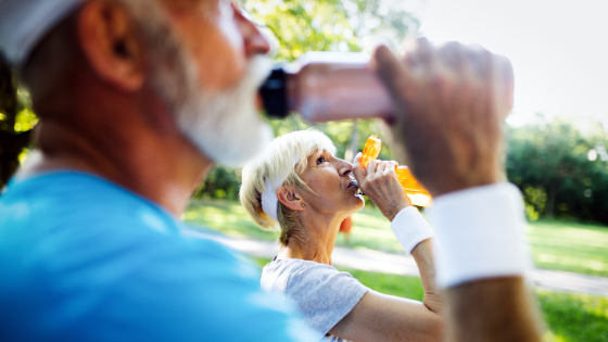 An older couple jogging in the park stop to drink water-6.png