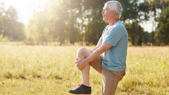 An older man is seen doing a single leg stand exercise in a field-4.png