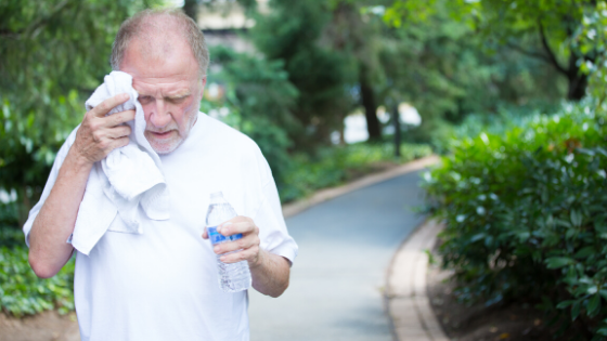 An older man is seen walking on a path, sweating and drinking water-1.png