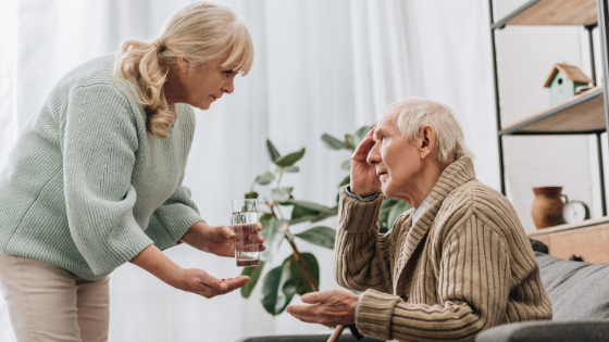 An older woman hands a confused elderly man a glass of water-1.png