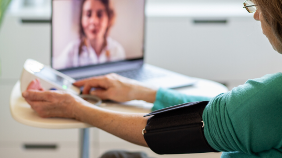 An older woman is seen taking her blood pressure while on a video doctor visit with her provider-1.png