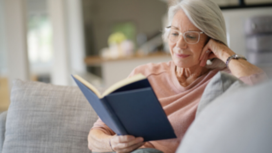 An older woman sits inside reading a book-9.png