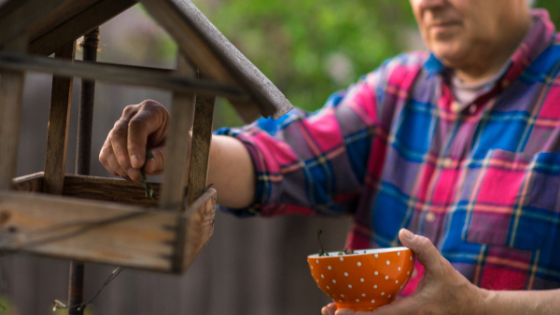 Close up of a senior man putting feed into his bird feeder-5.png