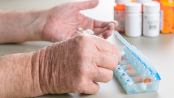 Close up of elderly hands organizing medications in a daily pill box-6.png