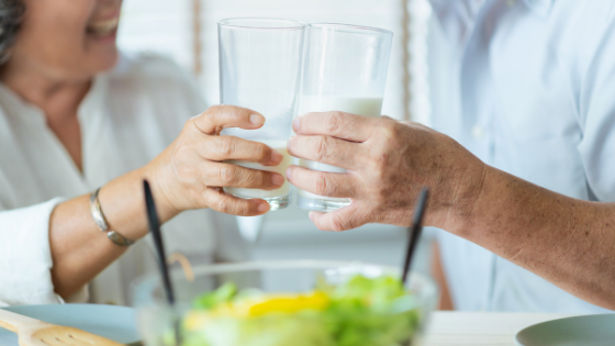 Close up of two seniors clicking glasses of milk, a salad in the background-12.png
