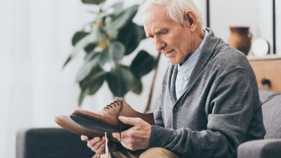 Elderly man is seen staring at two different shoes, looking confused-3.png