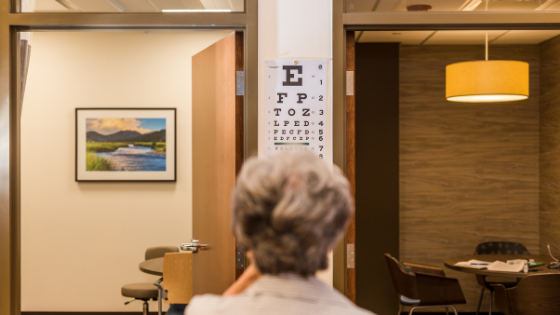 From behind, a older woman is seen taking an eye test-2.png