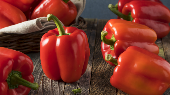 Half a dozen red bell peppers sit on a counter-2.png