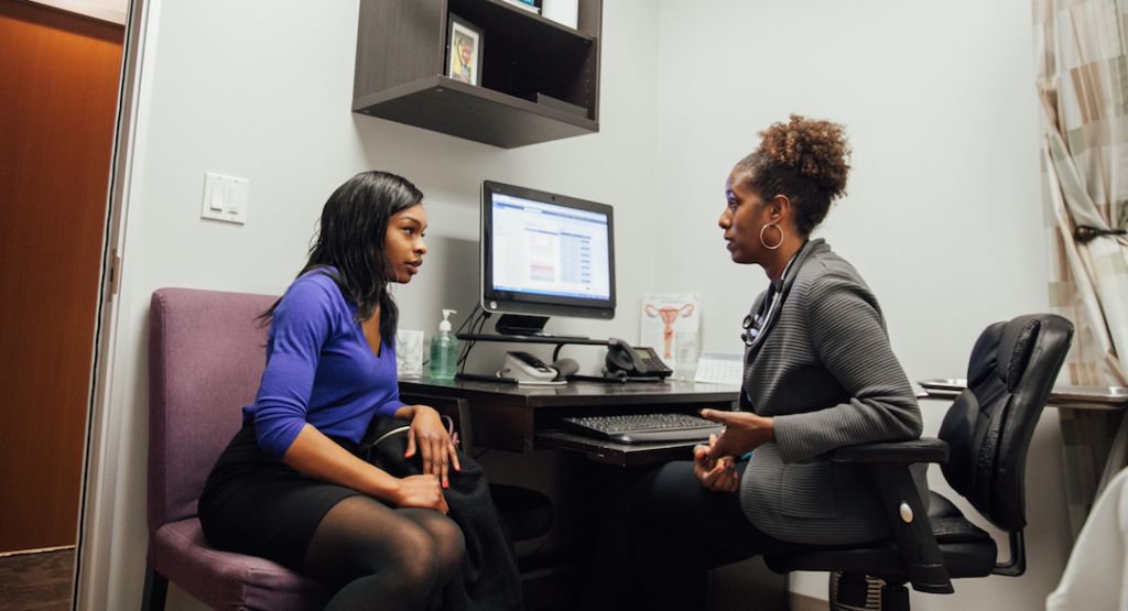 Female provider and patient talking in an exam room