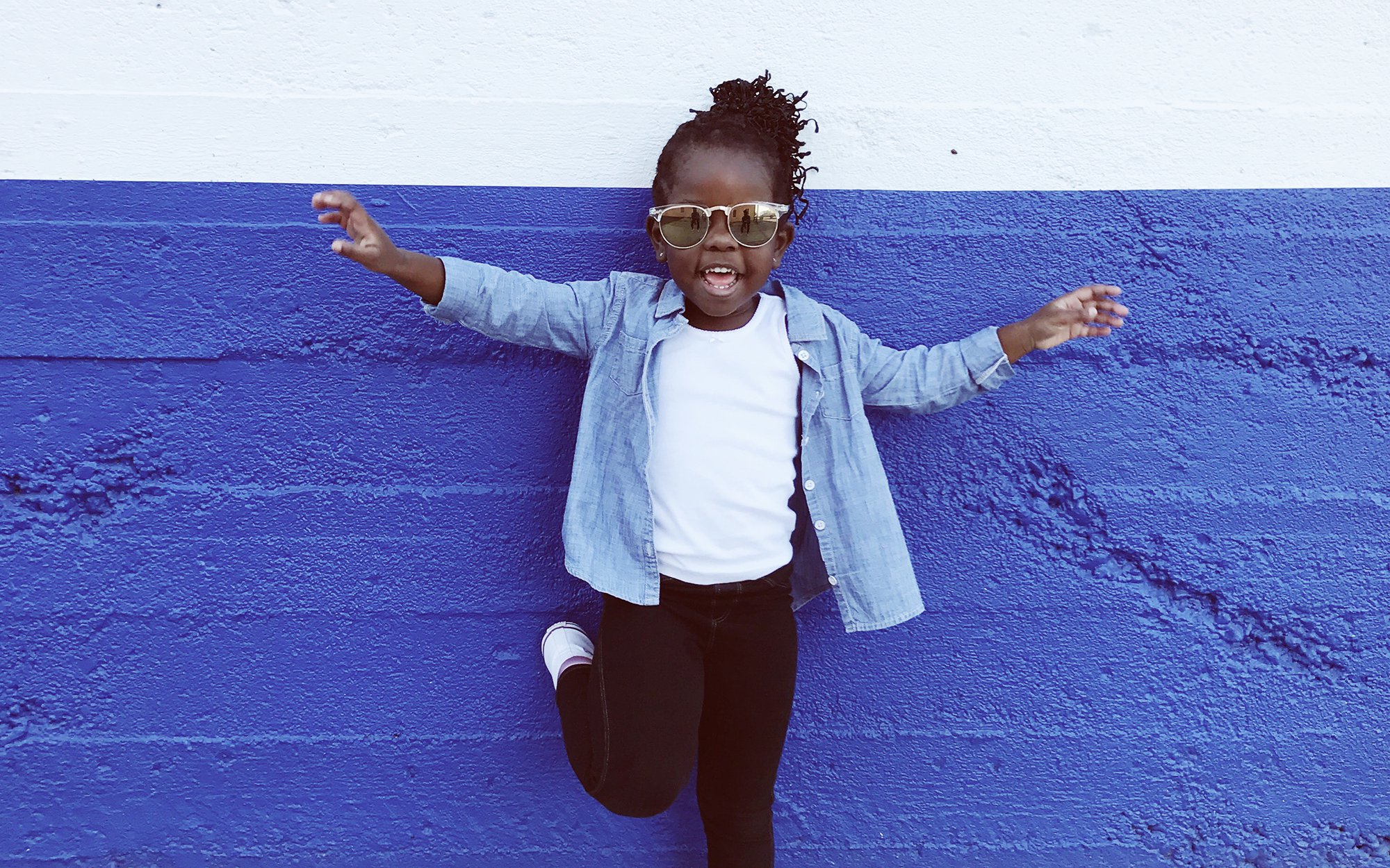 Little girl standing against blue wall.jpg