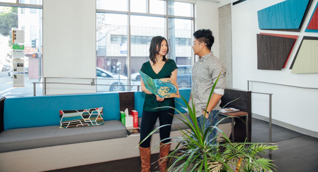 Two people in a modern office space looking at a book