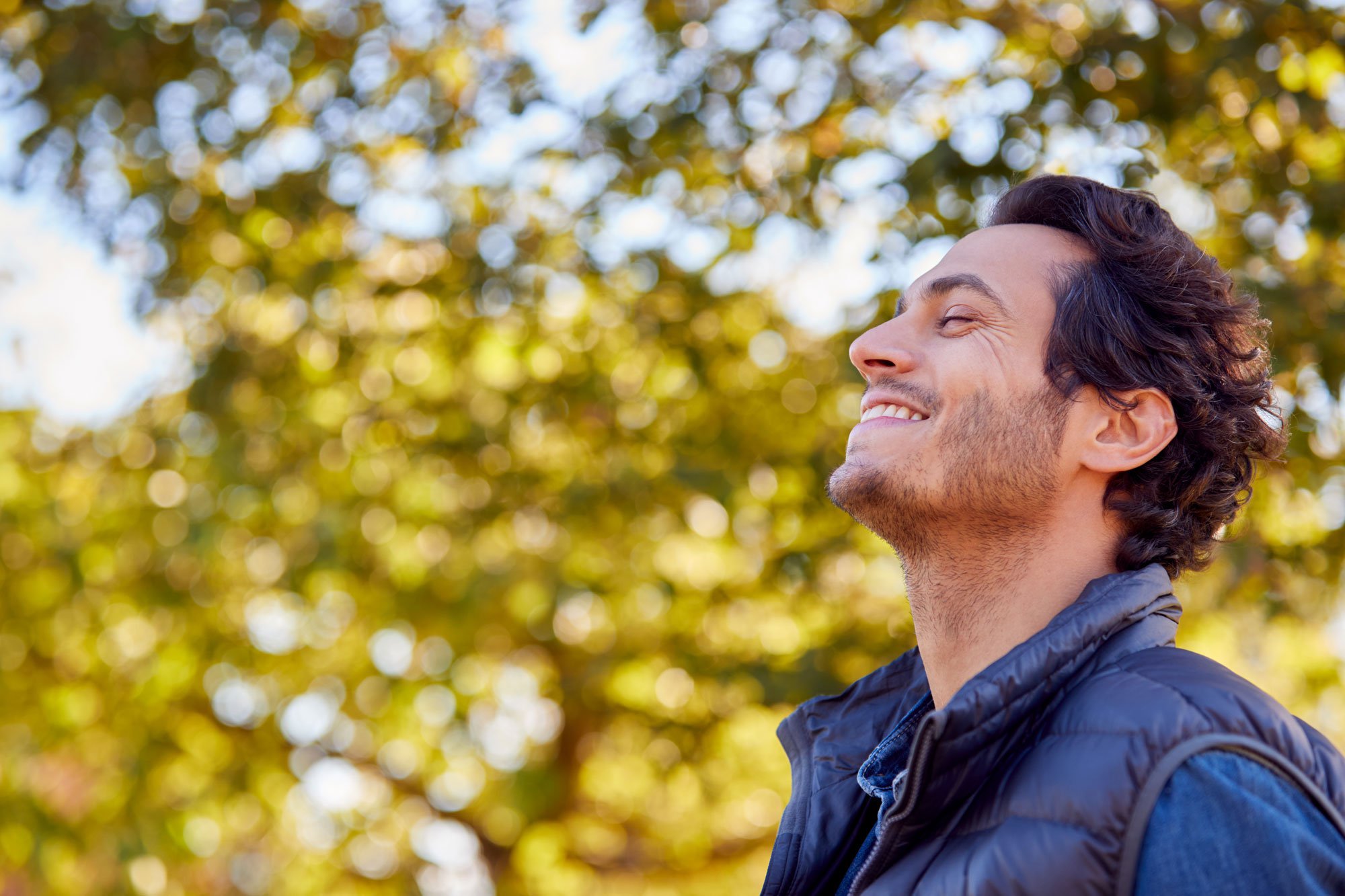 Man standing outdoors looking up and smiling