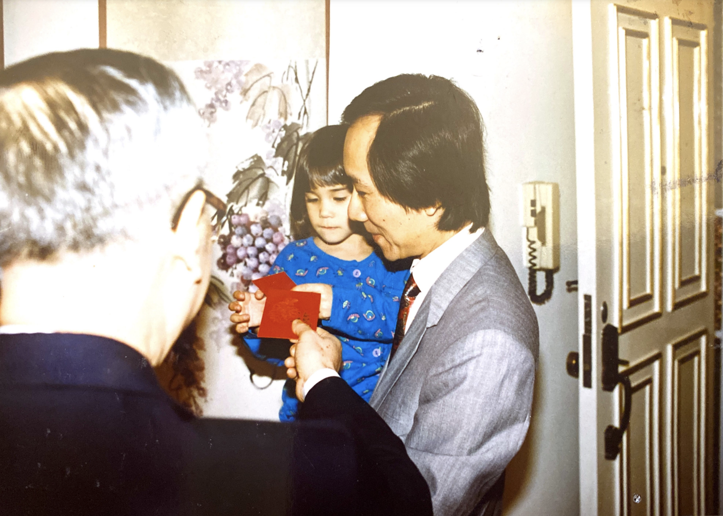 Annie as a child, being held by her father and receiving red envelopes for Chinese New Year.