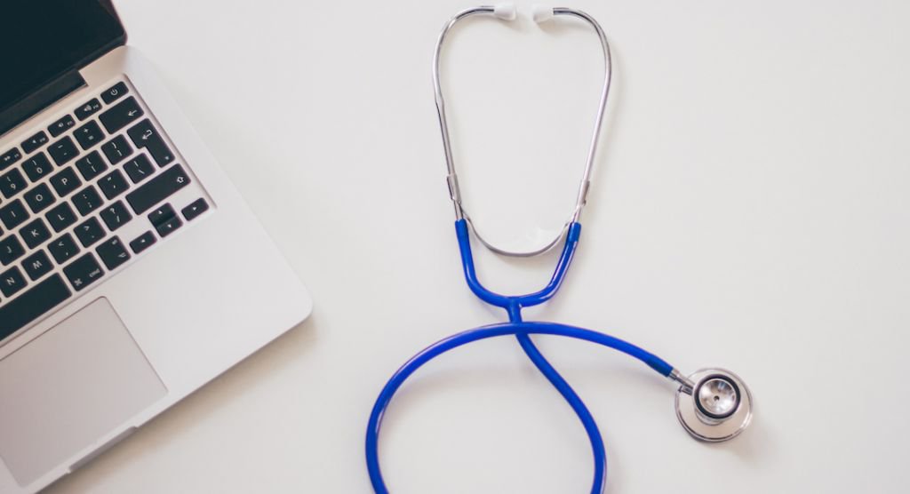 Close up of stethoscope next to a laptop computer