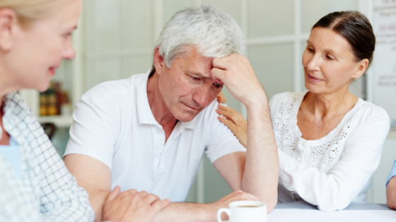 Two women comfort an upset older man with a cup of coffee-2.png