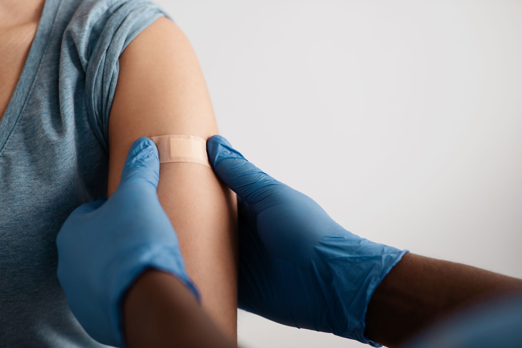 Person putting a bandaid on another's arm.