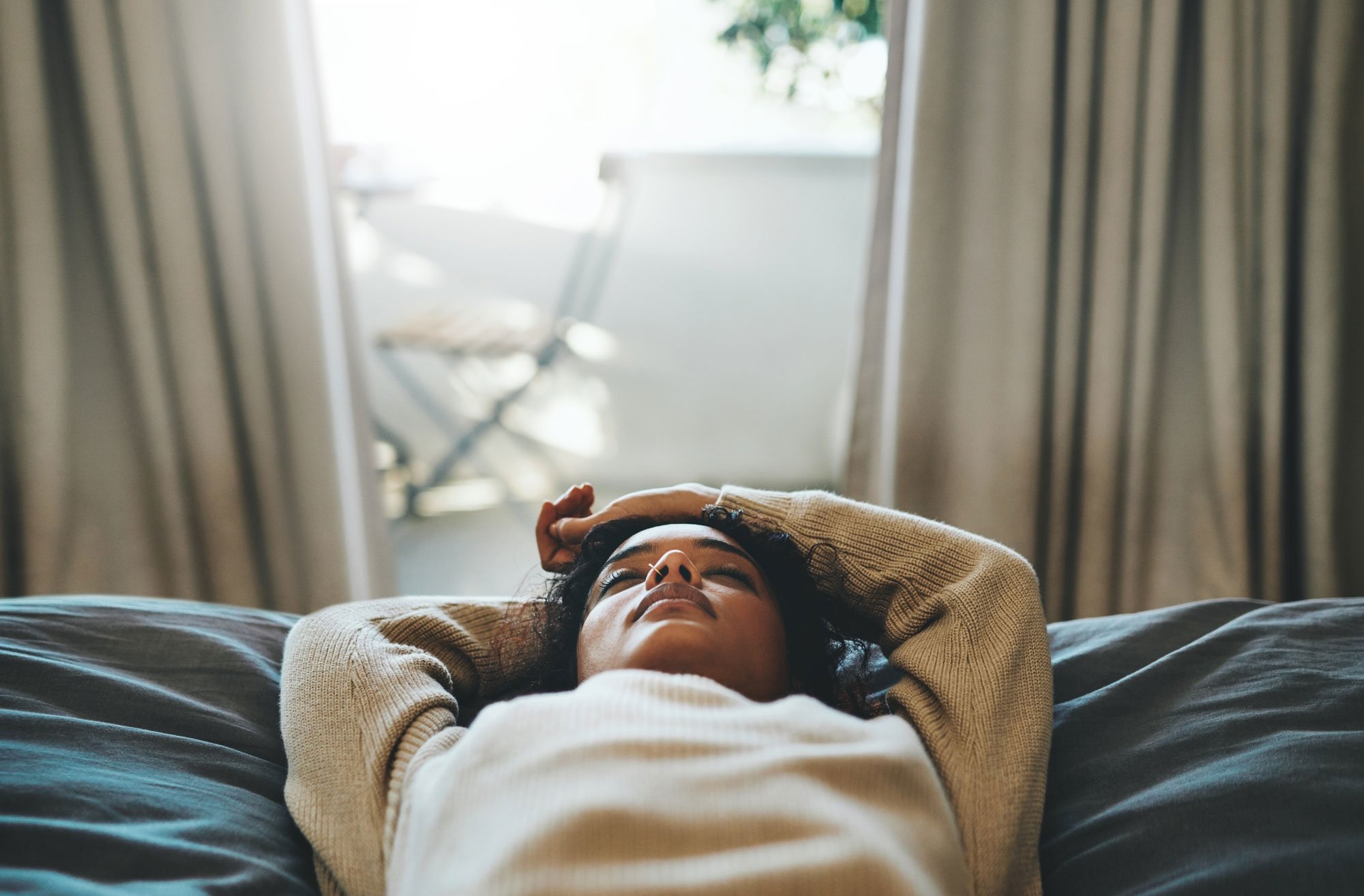 Woman laying on bed with eyes closed