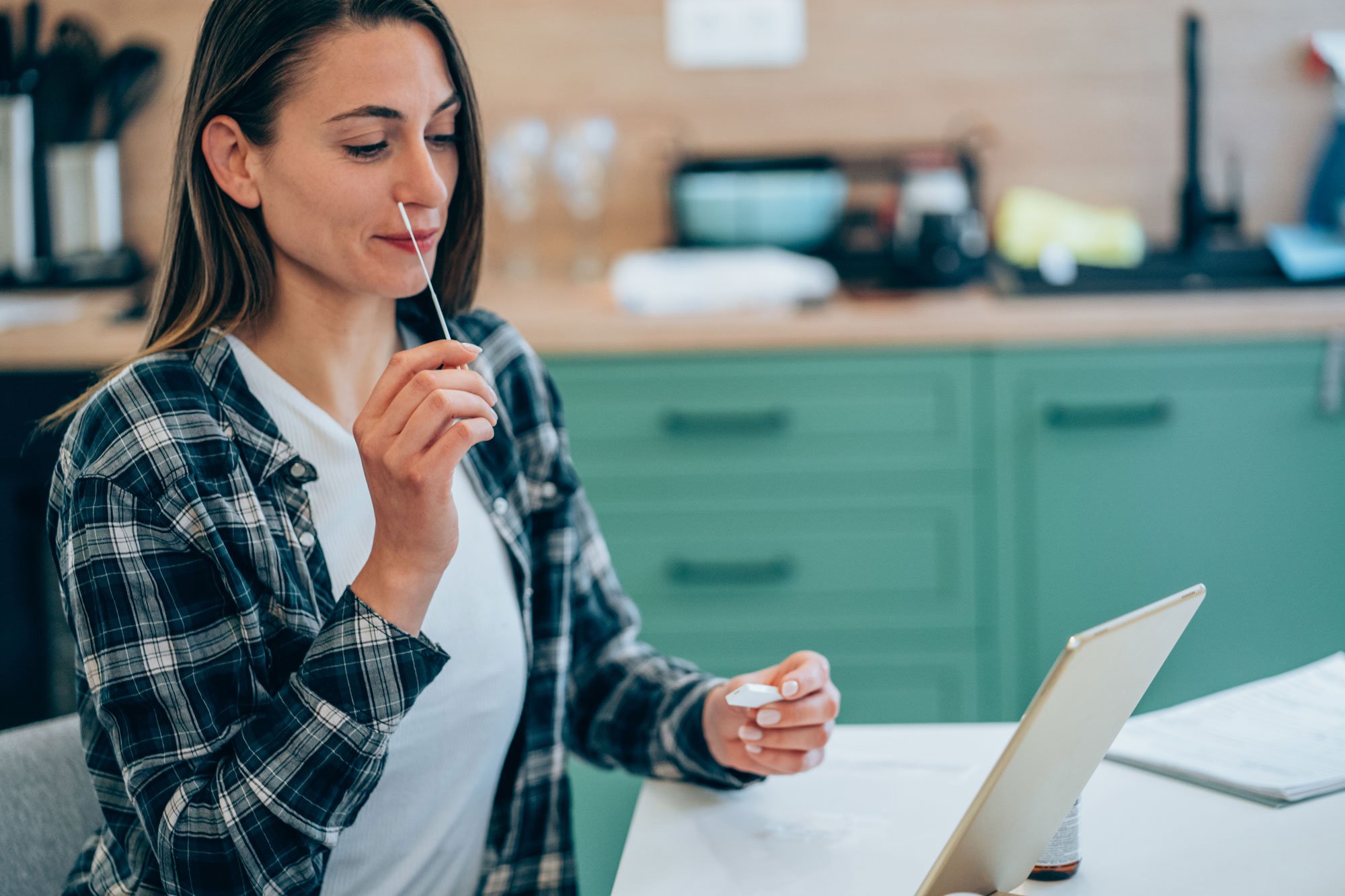 Woman holding nasal swab for at-home COVID-19 test