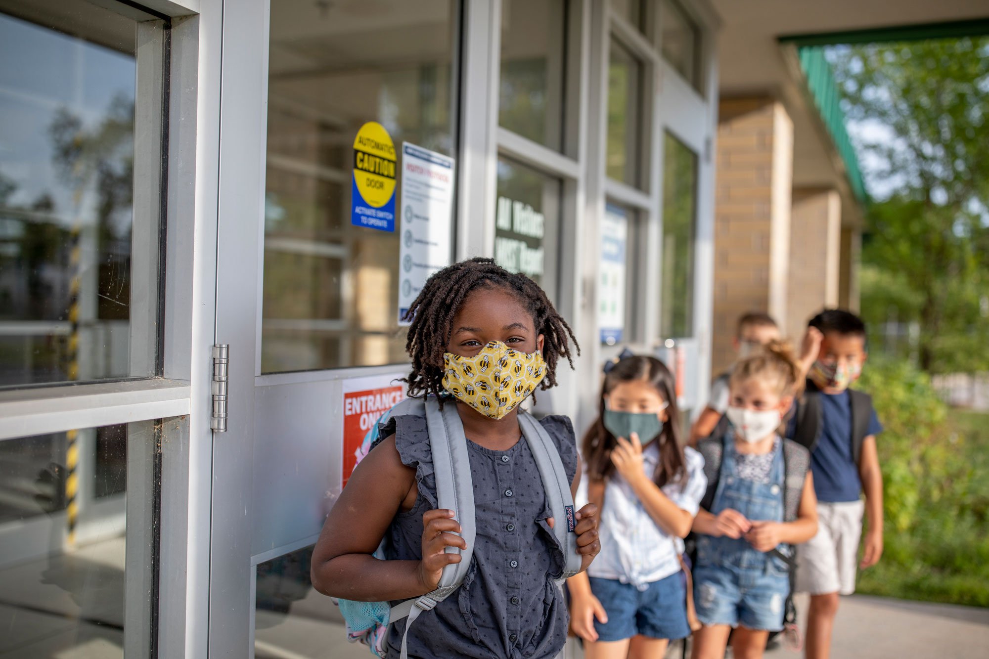 Kids lined up outside school wearing masks