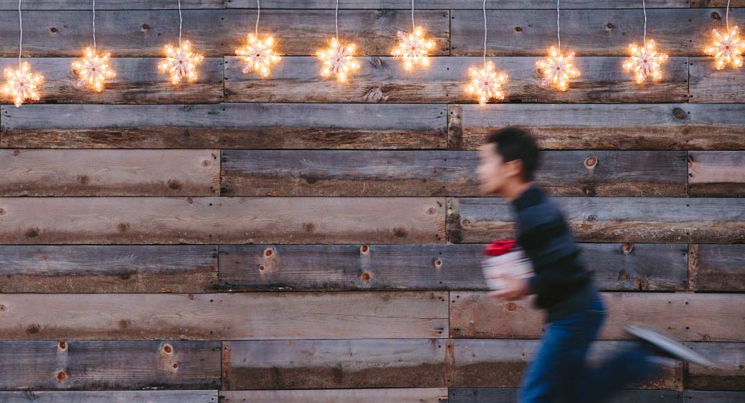 Boy running in front of wood and star lights