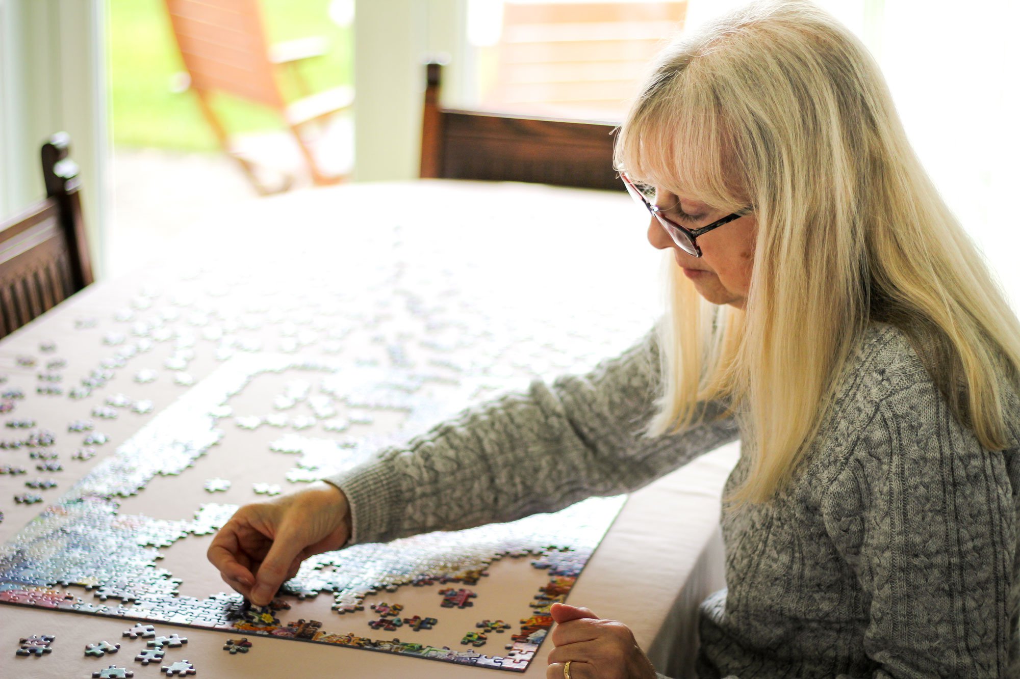 Senior woman doing jigsaw puzzle at table.