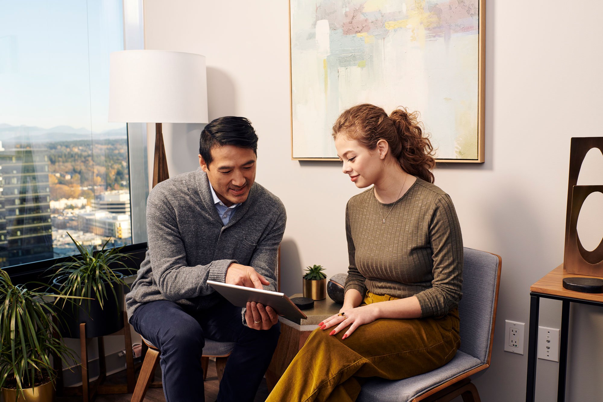 Doctor sitting next to young woman and showing her results on an ipad screen