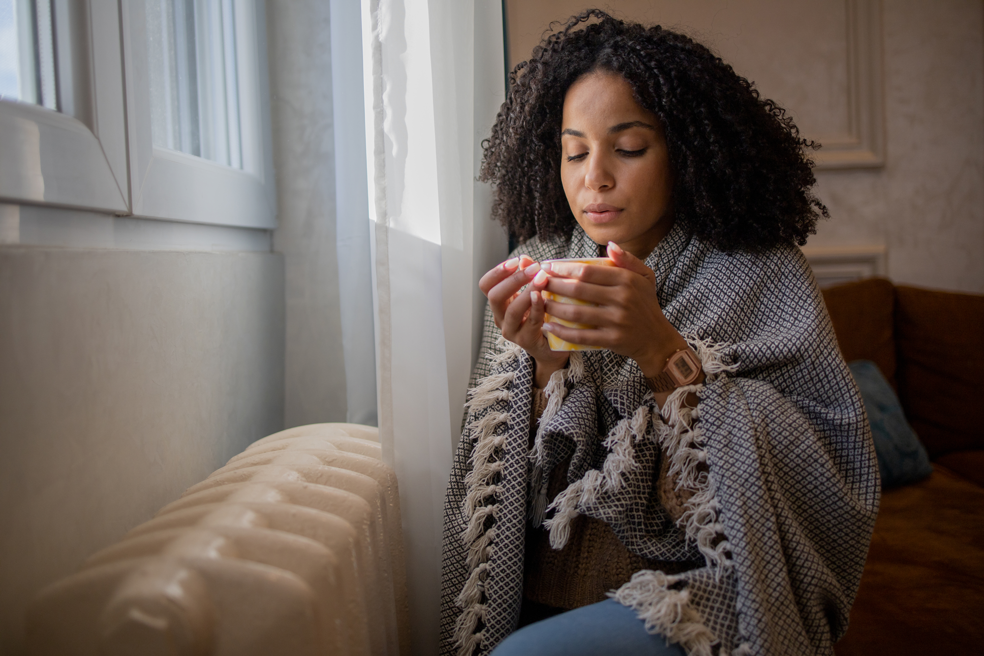 Woman wrapped in blanket and drinking from a warm cup