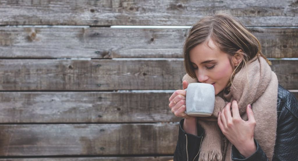 Woman in heavy scarf drinking from a mug