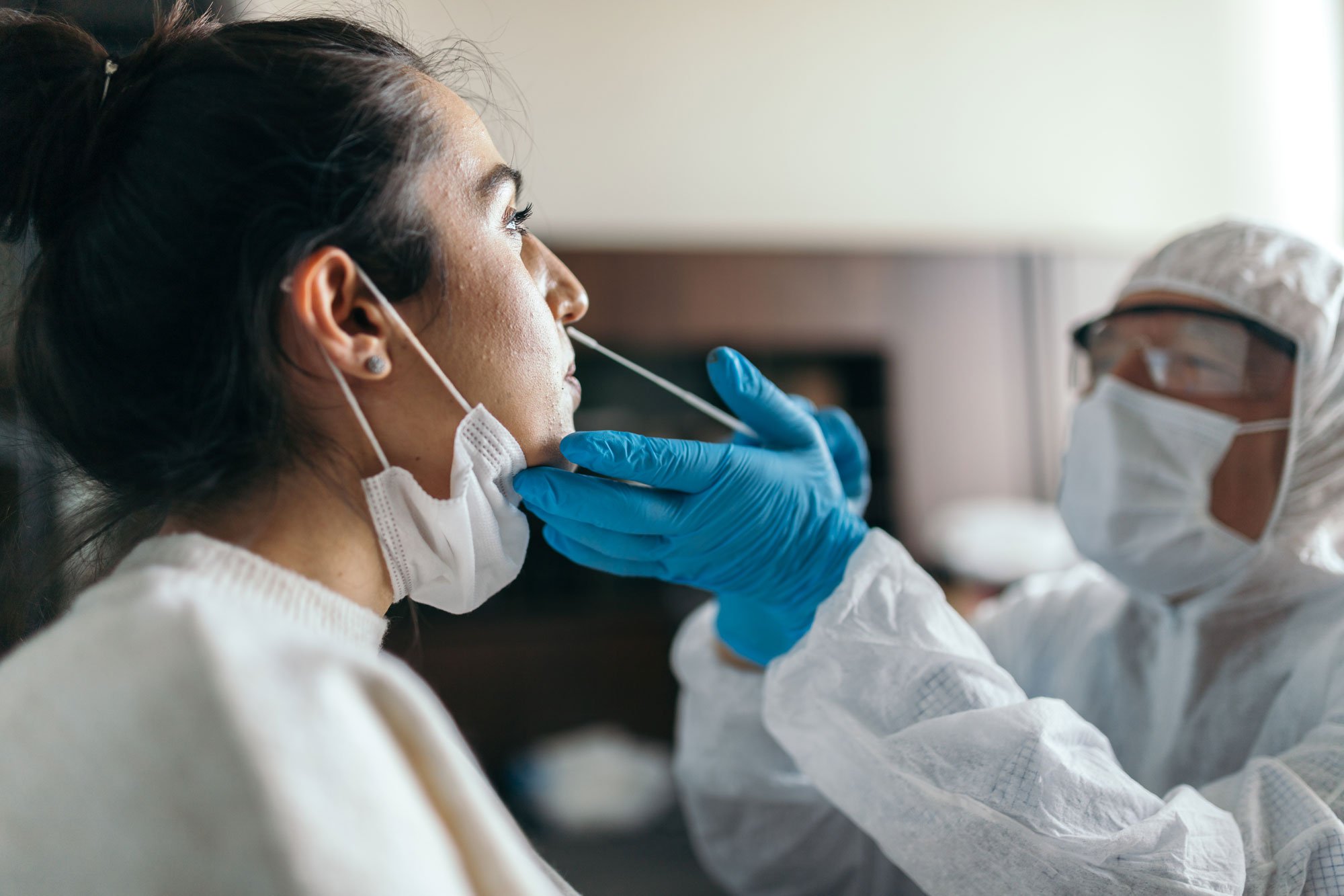 Doctor taking nose swab from young woman